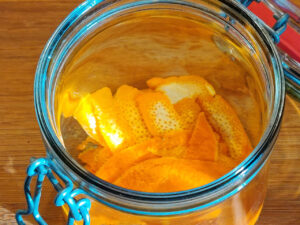 Orangenschale in ein Glas legen und mit dem Alkohol bedecken